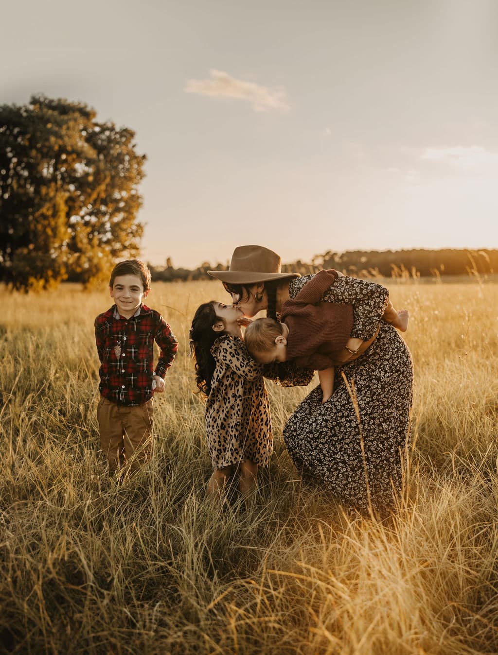 Family posing in a golden field at sunset in Brandon, Mississippi, during fall, showcasing warm autumn colors and candid moments.